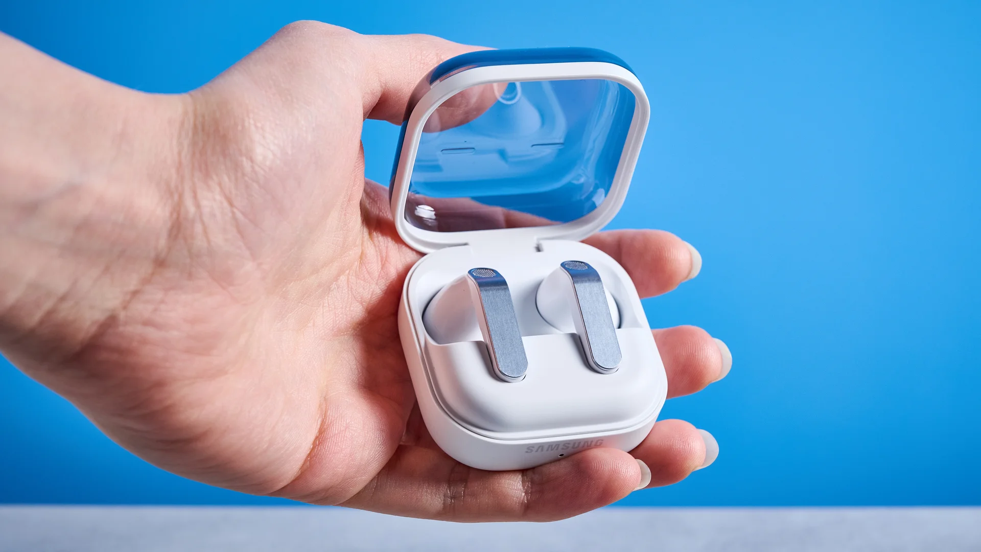the samsung galaxy buds 4 photographed against the blue tom's guide background showing charging case and buds
